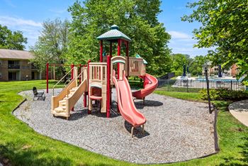 A playground with a red slide and a green roofed structure.